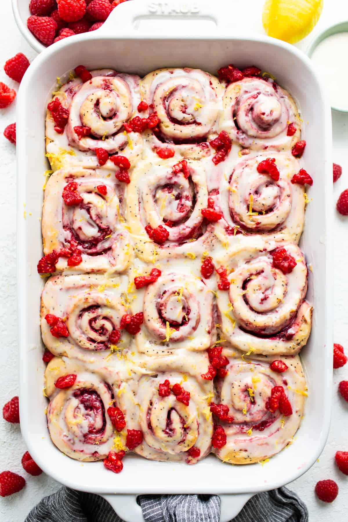 Raspberry cinnamon rolls in a white baking dish.