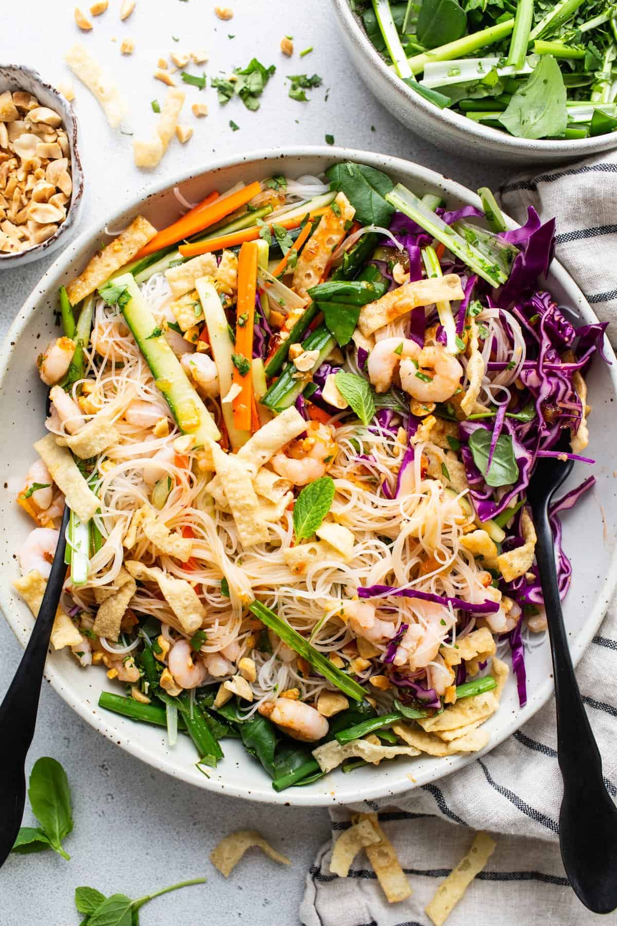 A bowl of asian noodle salad with peanuts and vegetables.