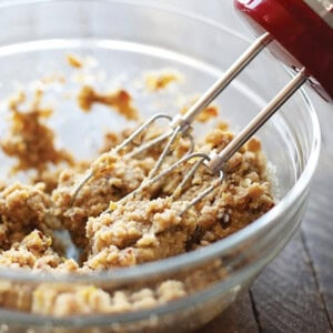 An electric hand mixer mixing almond flour biscotti dough in a glass bowl.