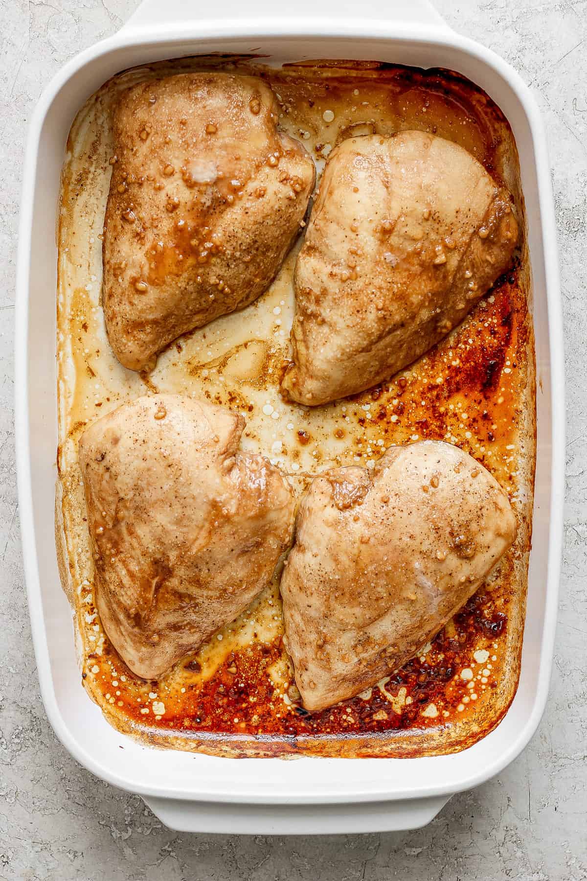 Raw chicken breasts marinating in a dish.