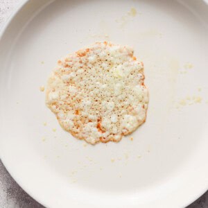 A single rice cake with scattered crumbs on a white plate.