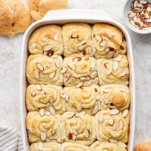 Freshly baked almond-topped sweet rolls in a white baking dish.