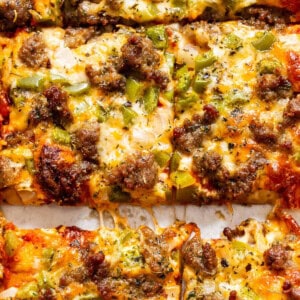 Close-up of a cheesy pizza with sausage and green peppers.