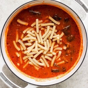 Pot of tomato soup with pasta on a kitchen counter.