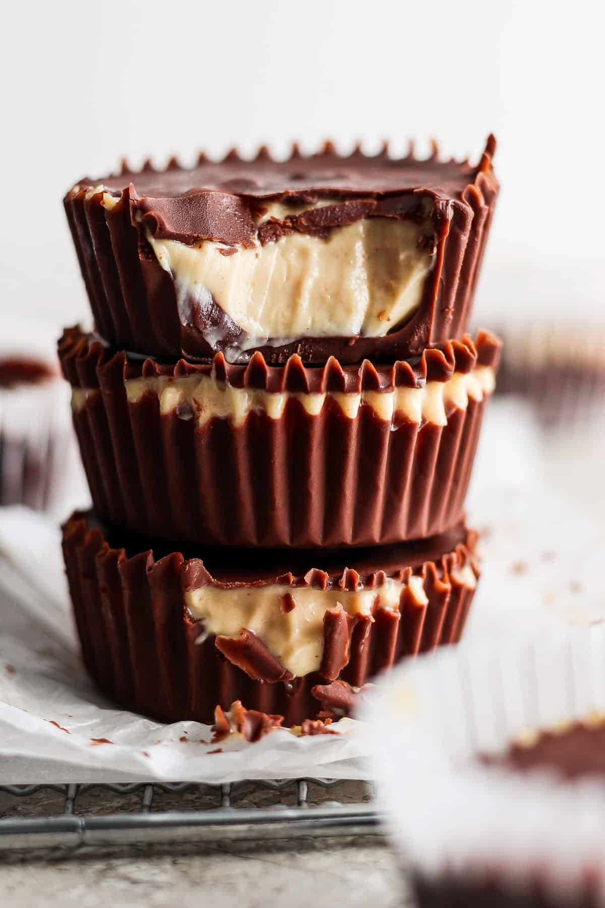 A stack of three homemade peanut butter cups with visible creamy peanut butter filling against a blurred background.