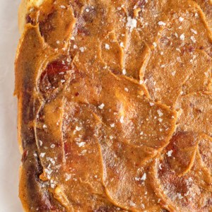 A close-up of a square piece of caramel-colored food that appears to be swirled with light and dark streaks and sprinkled with coarse salt on top.