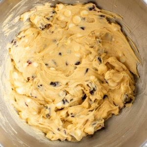 A metal mixing bowl containing a dough mixture with visible chocolate chips and white chunks.