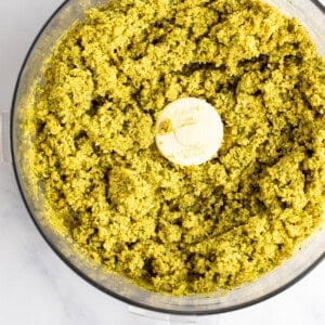 A food processor filled with blended green pesto.