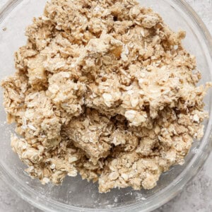 A glass bowl containing a mixture of oats and flour sits on a grey countertop.