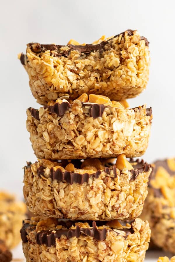 A stack of four granola clusters with visible chocolate coating and peanut toppings, arranged on a light background.