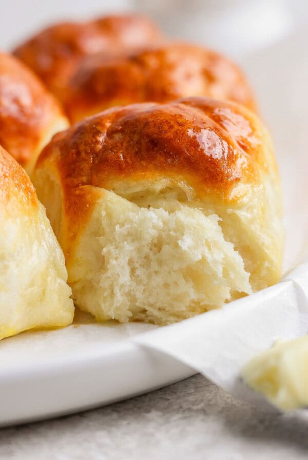 Close-up view of freshly baked, golden brown bread rolls on a white plate.