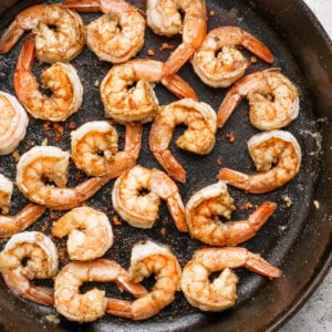 Cooked shrimp seasoned with spices in a black skillet.