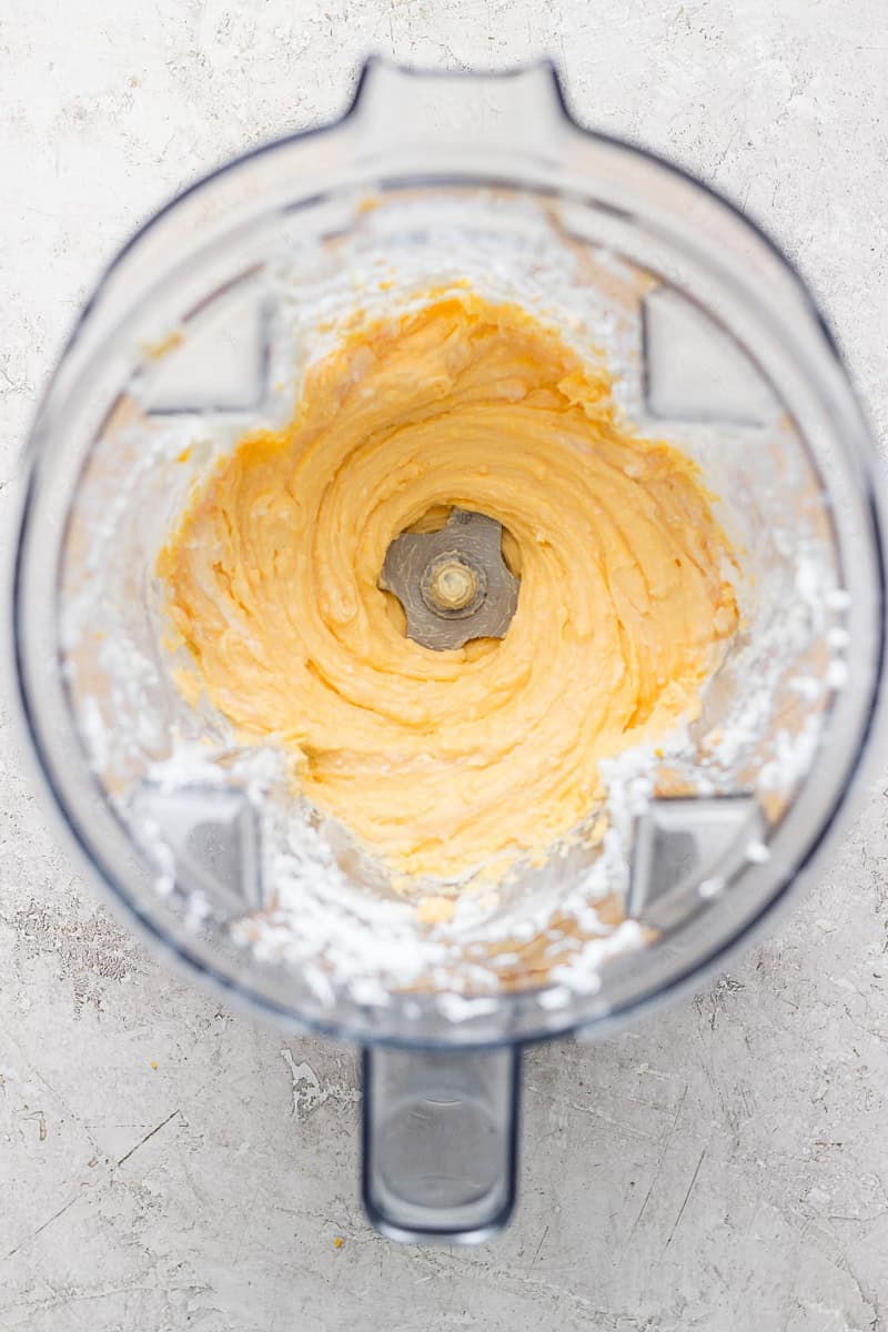 Top view of a blender with creamy, whipped mixture inside, surrounded by a dusting of white powder on the container's edges.