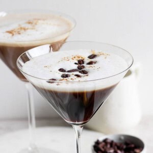 Two classic espresso martinis served in chic martini glasses, each boasting a frothy top and perfectly placed coffee bean garnish.