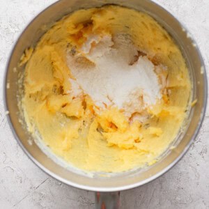 Mixing bowl with creamed butter and sugar on a textured surface.